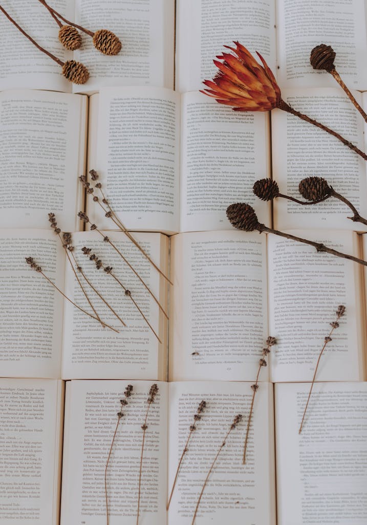 Delicate dried flowers and foliage on open books create a serene and artistic composition.